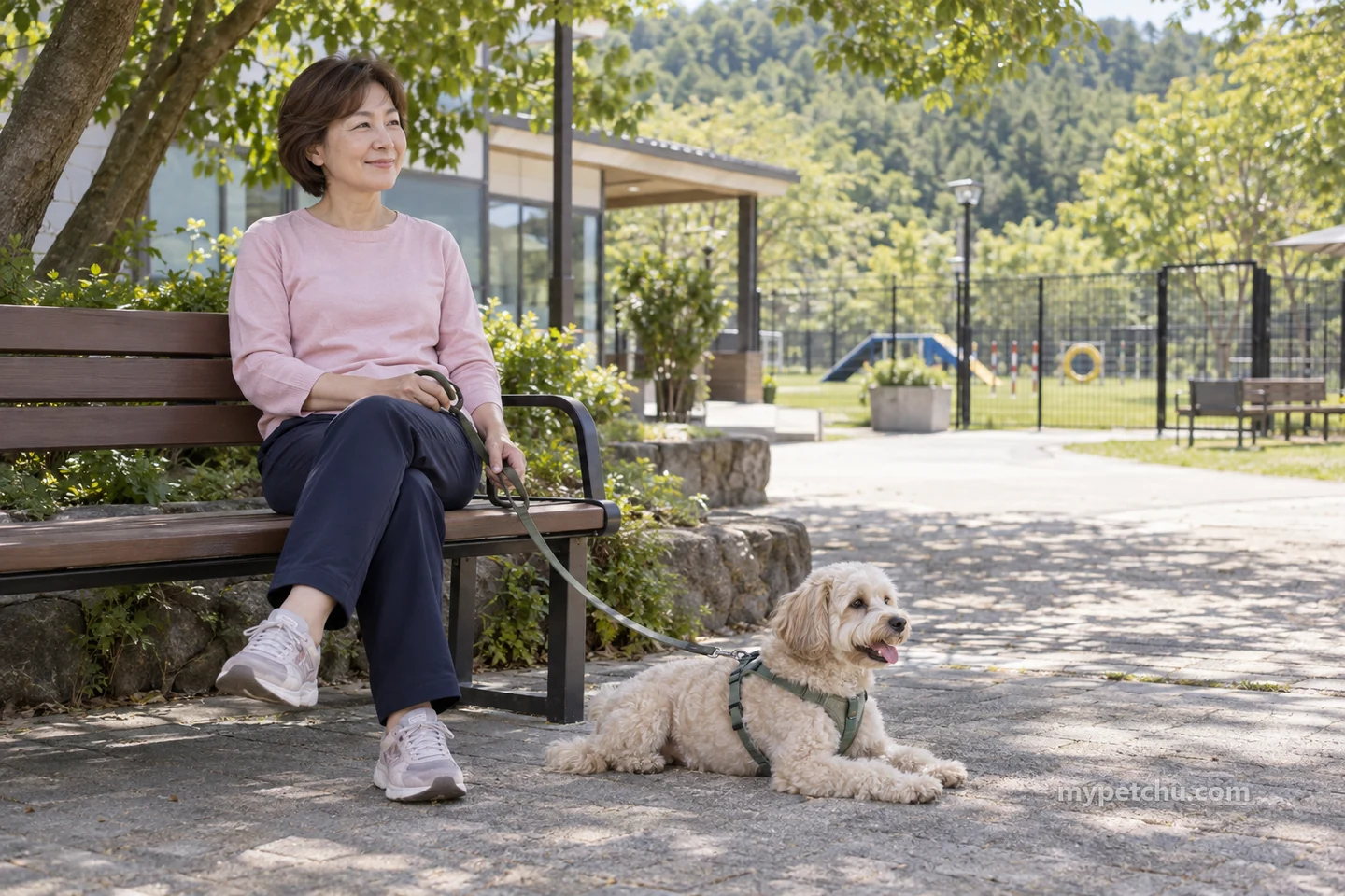 그늘 벤치의 보호자가 가슴줄에 연결된 줄을 잡고 개는 곁에서 쉬는 모습