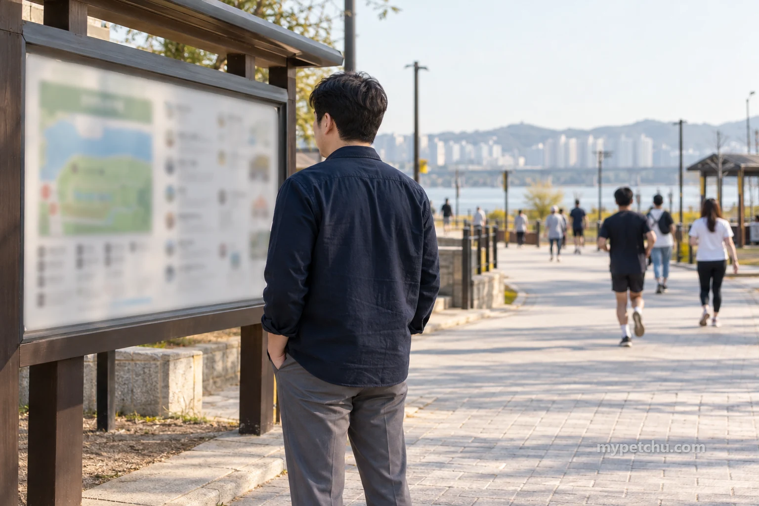 사람들이 지나는 야외 보행 공간의 안내판을 바라보는 보호자