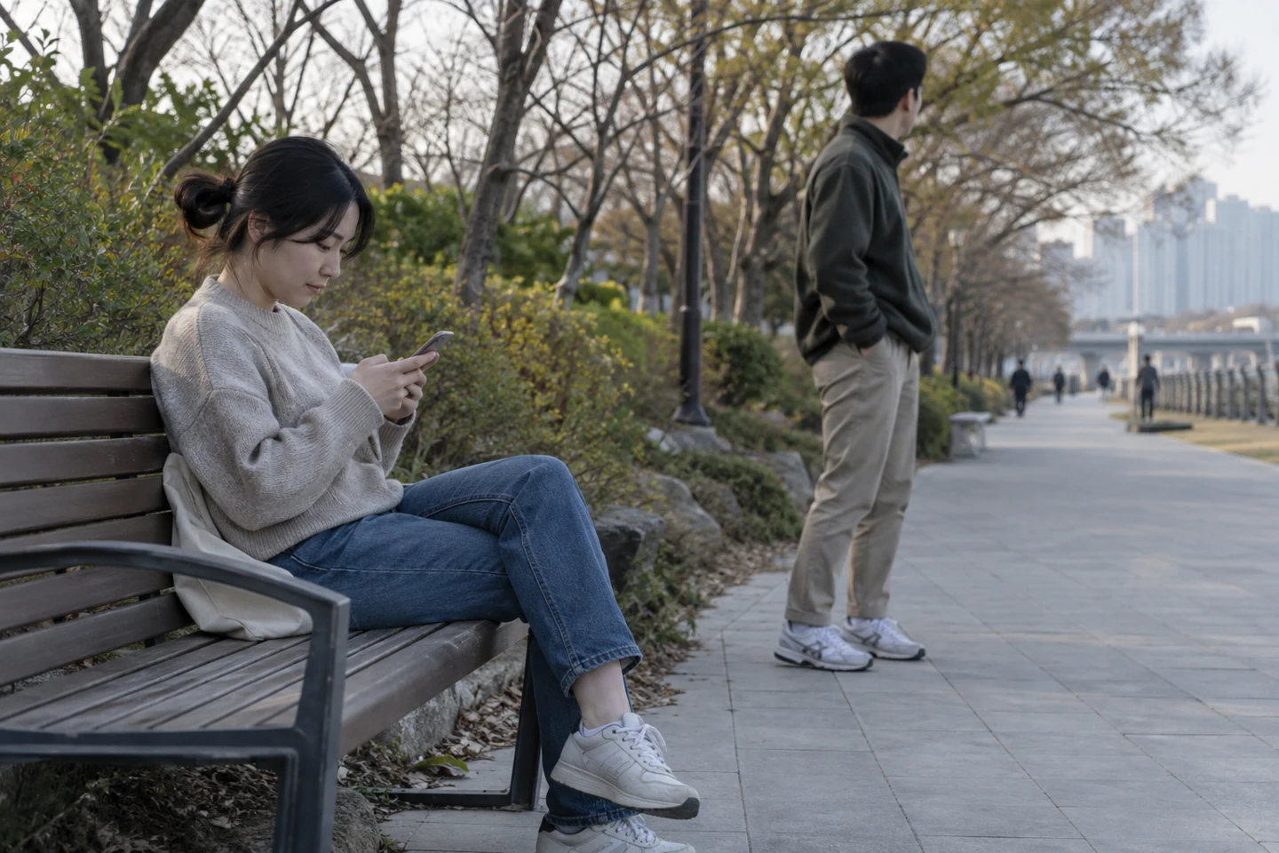 벤치에서 휴대전화를 보는 사람과 길을 살피는 사람