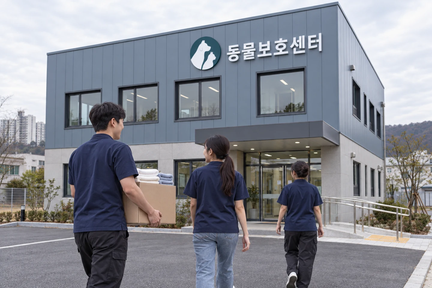 보호센터 입구로 상자를 들고 걸어가는 세 사람
